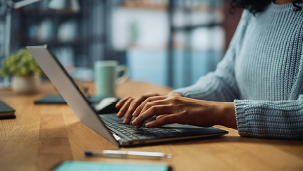 A woman’s hands on a laptop keyboard.