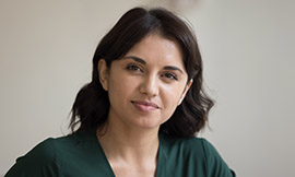 headshot of woman with dark hair wearing a dark green shirt and smiling at the camera