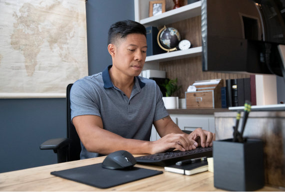 man sitting at a desk while typing on a keyboard