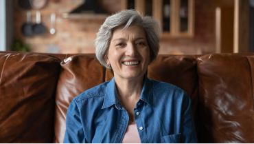 Smiling older woman sitting on leather couch